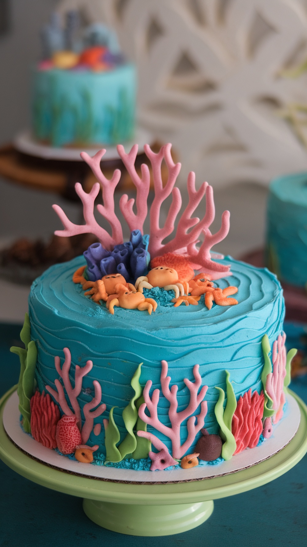 A colorful underwater coral reef cake with blue frosting, pink and purple coral decorations, and small sea creature figures.